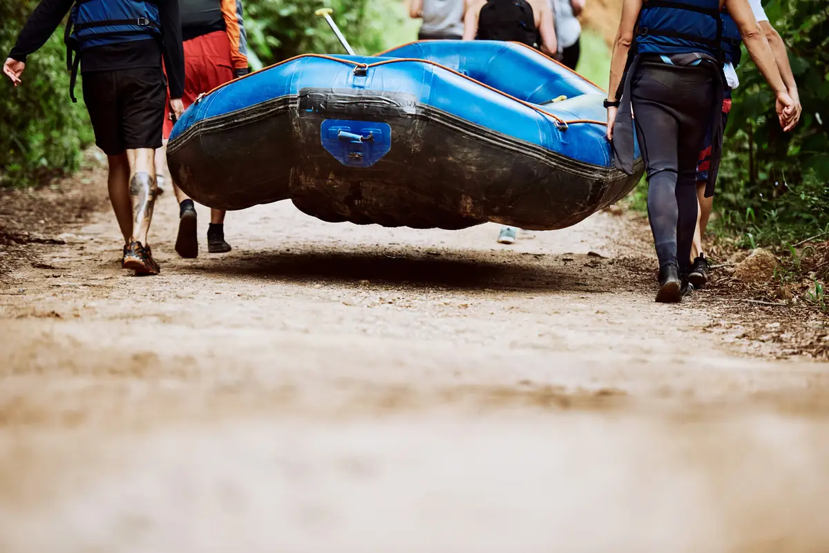 A crew carrying a raft down the trail to the river