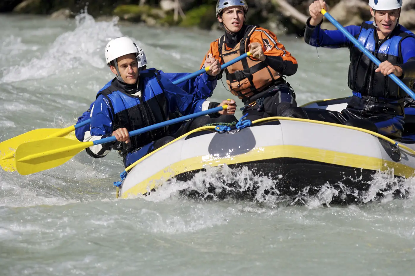 A crew paddling a raft through a rapid