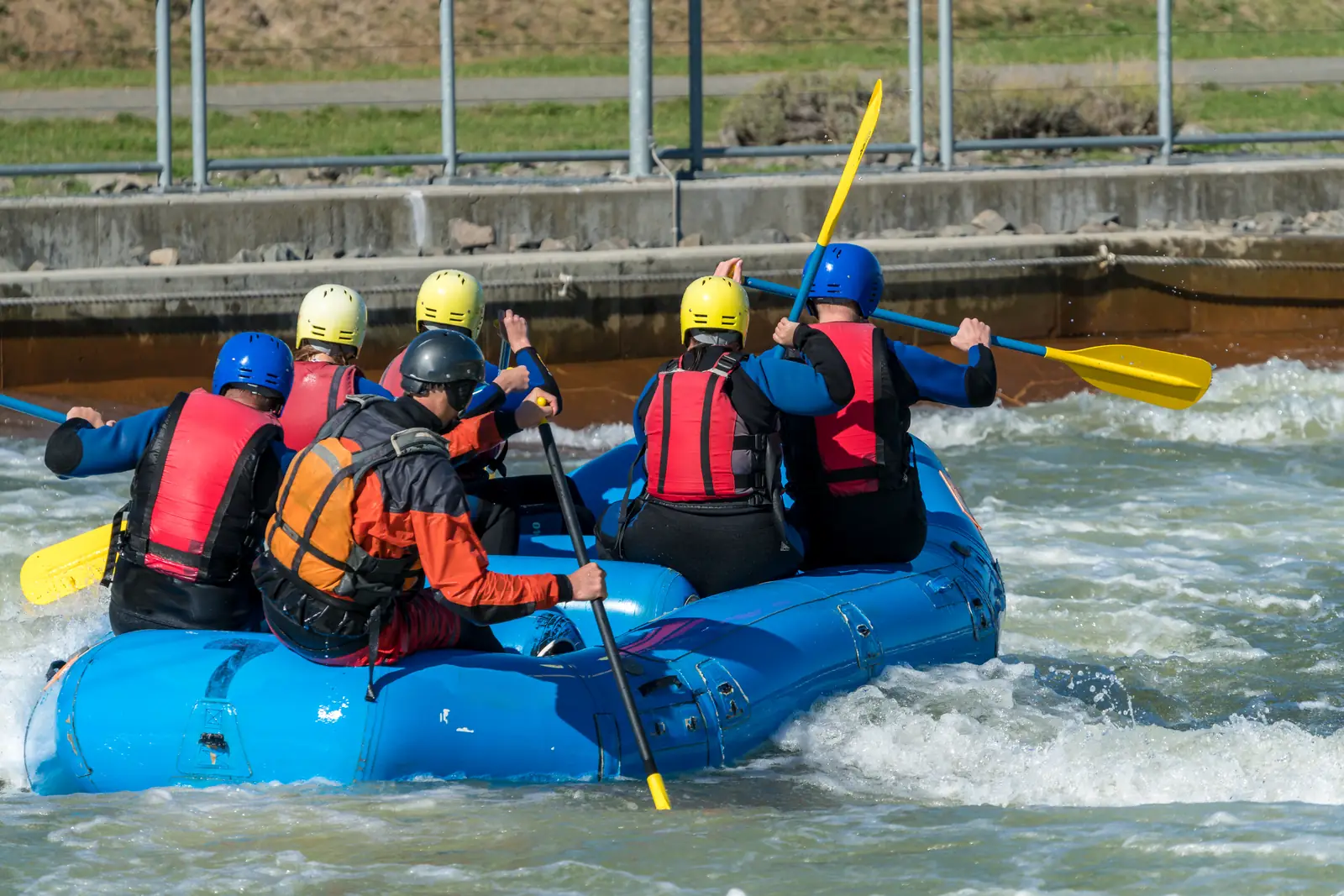 A group in a blue raft paddling through whitewater